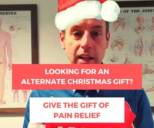 Dave our chiropractor in a Santa hat holding a pain kit